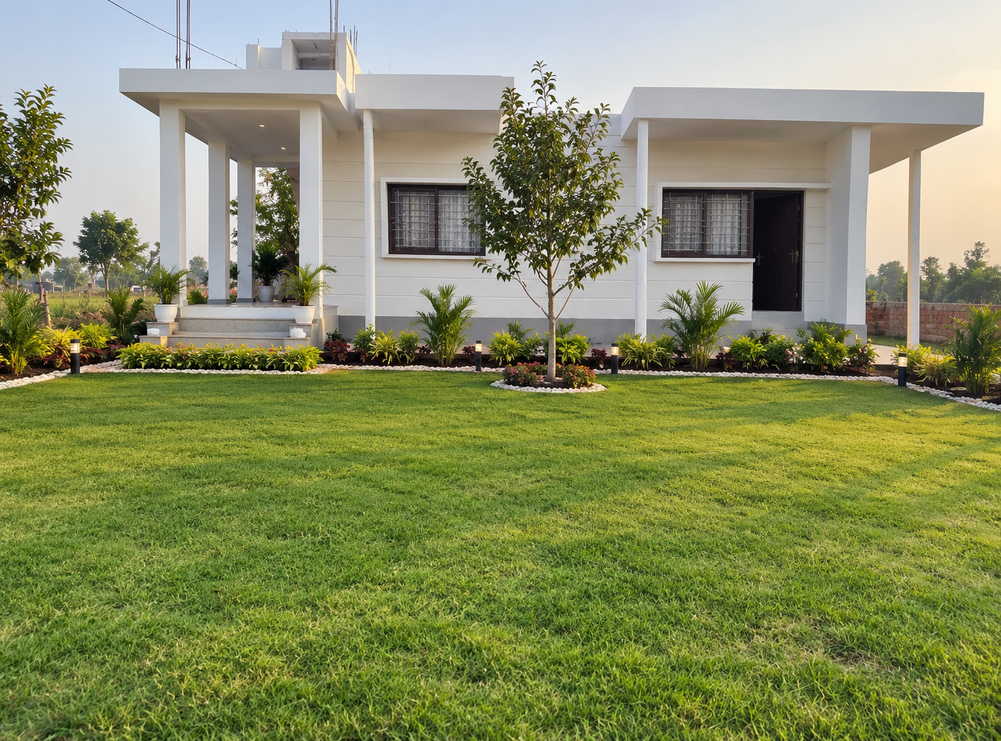 Second exterior view of the villa in Darbhanga, showing the entrance, lawn and garden